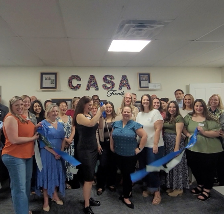Marissa Austin cuts the ribbon officially opening the Patti Hewitt Training Room with CASA Wilco staff, volunteers, board members and donors behind her. Photo by Nalani Nuylan.