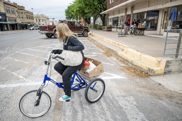 Bethany Wright, with food received from Shepherd’s Heart Food Pantry, leaves the pantry site on her trike on Saturday, March 28, 2026.  Shepherd’s Heart Food Pantry and Thrift Shop, at 121 East 2nd Street, was founded by Executive Director Loretta Masters in 1994.  The group distributes food several times a week.  In 2025 Shepherd’s Heart averaged 2,110 distributions a month.    Photo by  Andy Sharp.