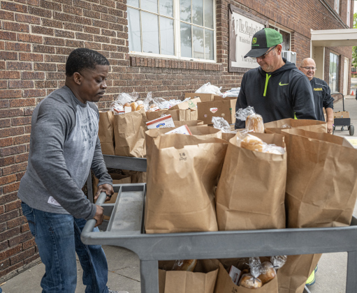 Volunteer Fred Dunn, left, wheels out food items for distribution at Shepherd’s Heart Food Pantry  on Saturday, March 28, 2026.  Shepherd’s Heart Food Pantry and Thrift Shop, at 121 East 2nd Street, was founded by Executive Director Loretta Masters in 1994.  The group distributes food several times a week.  In 2025 Shepherd’s Heart averaged 2,110 distributions a month.    Photo by  Andy Sharp.