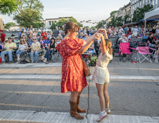 Taryn Hansen dances with her daughter Fiona, 8, as they enjoy a performance by Dysfunction Junction on Friday, April 24, 2026, the first night of the Red Poppy Festival.    Photo by  Andy Sharp.