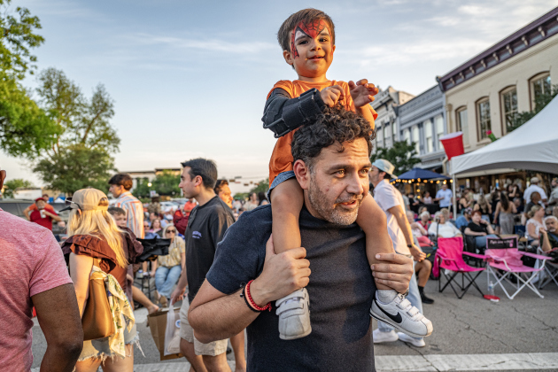 Two-and-a-half year-old Alonso Gonzales sits on the shoulders of his grandfather Juan Carlos Andrade as they listen to a performance by Dysfunction Junction on Friday, April 24, 2026.