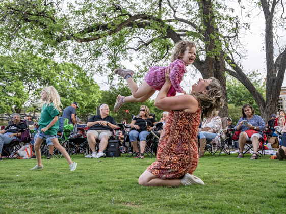 Rachael Dunn and her daughter Carly, 2, were enthralled as they enjoyed the music of Supernatural ATX, a Santana Tribute Band, during the first First Friday free concert of the year on the courthouse lawn on Friday, April 3, 2026.  The event was hosted by the Georgetown Beard Club.   Photo by  Andy Sharp.