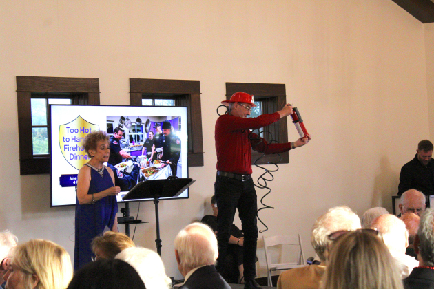 Fireman Steve Terry keeps attendees safe while promoting a lunch with Georgetown firefighters as one of the auction items at the event. Auctioneer Gayle Stallings (left) was the night’s Master of Ceremonies.