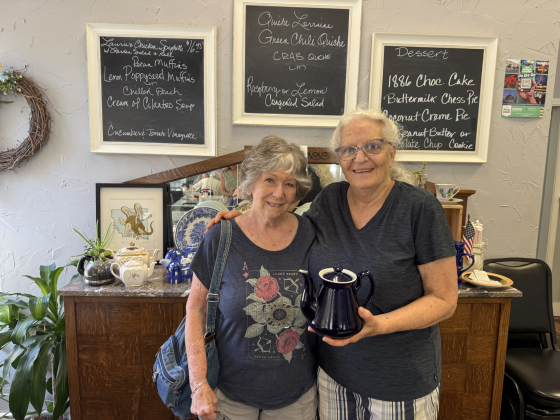 Customer Jean Little (left) gave Owner Beth Ernest (right) one of her mother’s old teapots to display in Laurie’s Cafe. Standing in front of the chalk boards with the specials at Laurie’s Cafe on 612 South Main Street. Photo by Abbey Archer