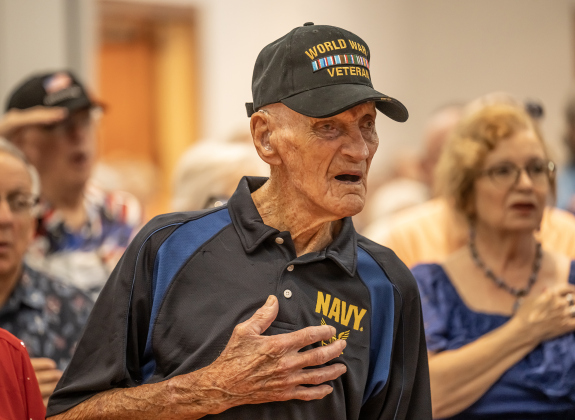World War II Navy veteran Cliff McCrummen, who will be 100-years-old on June 23rd, salutes and sings during the playing of the National Anthem at the Memorial Day ceremony held in Sun City on Monday, May 25, 2026.  Photo by Andy Sharp.
