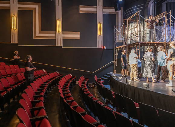 Faith Castaneda, the Palace Lighting and Production Manager, stands at left in the seating area minutes before the opening of  the  Thursday, May 28, 2026 dress rehearsal for “Jesus Christ Superstar,” playing on the Georgetown Palace Springer Stage through July 5th.  The seats will be replaced with new ones in September.   The Palace is once again operational after flooding that occurred on January 25th.  Photo by Andy Sharp.