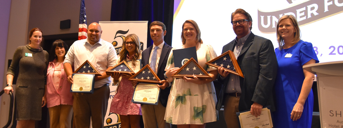 From left, Christie Parker-Wheeler, from the Rotary Club, Marie Alvarado, from Congressman John Carter’s office, and winners Bretton Schulz, Madison Runyan, Collin Buckley, Megan Mills, Seth Gipson and Chamber of Commerce President Shontel Mays at the 5 Under 40 Awards on May 8. The award winners are holding flags, courtesy of Mr. Carter’s office, that have been flown over the nation’s capitol building. (Photo by Kaitlyn Wilkes) 