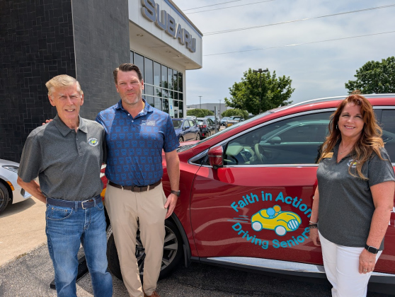 Faith in Action Board Member Jim Wilson, Subaru of Georgetown GM Dan Azel,  and Faith in Action Executive Director Lisa Hoy stand with a vehicle. 