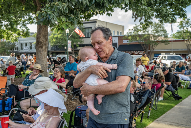 Brett Hoskins embraces Thomas Alexander Davidson, his 7-month-old grandson  while  music is  played by  Vinyl Countdown G/ATX! during the free First Friday concert held on the Williamson County Courthouse lawn on Friday, June 12, 2026.  The concerts, hosted by the Georgetown Beard Club, are generally on the first Friday of the month, but this one was postponed because of rain last week.     Photo by Andy Sharp