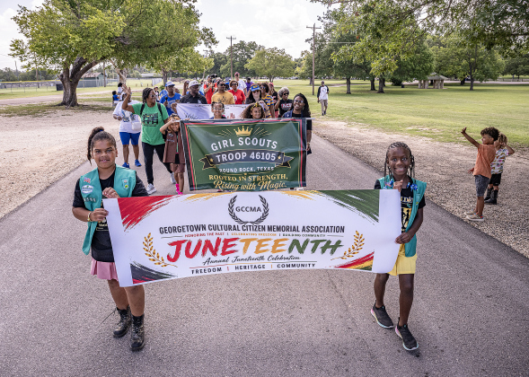 Leila Milks, 9, left, and Skylar Savoy, 9, right,  with Girl Scout Troop 46105,  lead a parade through San Gabriel Park during the 74th Annual Juneteenth  Celebration held at the Georgetown Community Center on Saturday, June 13, 2026.  The event is hosted by the Georgetown Cultural Citizen Memorial Association.    Photo by Andy Sharp. 