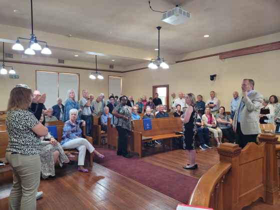 More than 100 Sun City residents stay in the Commissioners Courtroom after the meeting to oppose the Road District tax. County Judge Steve Snell (far right) and Rachel Arnold, executive assistant to Commissioner Valerie Covey (center right), answers questions from the residents. Photo by Nalani Nuylan.