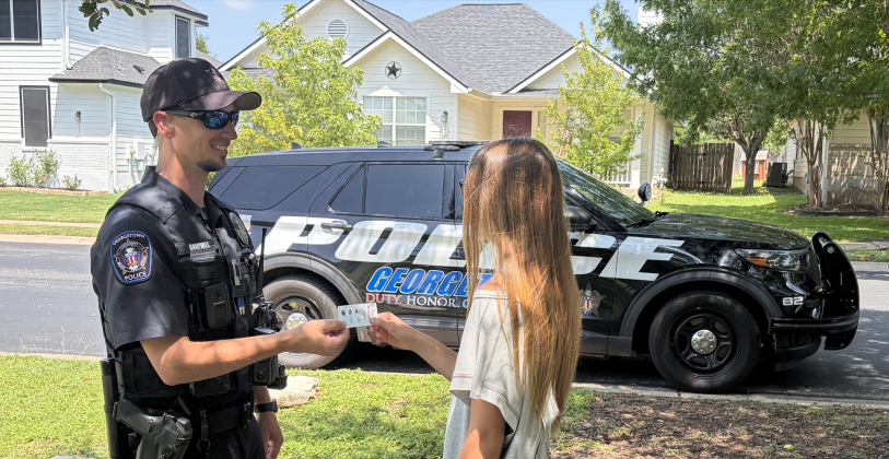 Officer Eric Campbell, left, hands out a coupon for safe behavior. (Photo courtesy Georgetown Police Department)