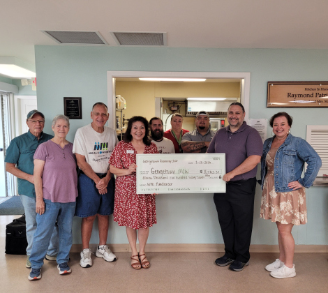 Raymond Husser, from the Georgetown Running Club (center right) presents a $11,562.37 check to Opportunities for Williamson and Burnet Counties’ Meals on Wheels program at the Georgetown Meals on Wheels location, 803 West Eighth Street, on July 10. Meals on Wheels staff and volunteers accompany Mr. Husser. Photo by Nalani Nuylan.