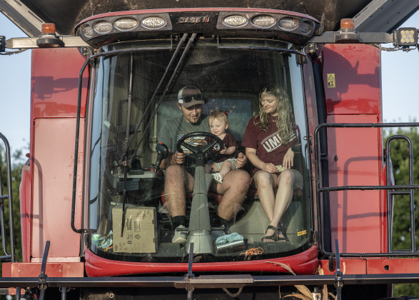Montgomery Raesz, his wife Madalynn and their daughter Maizlee, 16-months-old, prepare to guide a combine through a field of corn along County Road 101 during the 2026 corn harvest of brothers Shaun and Steven Raesz on Saturday, July 11, 2026.  Montgomery, 26,  is the first-born son of Shaun Raesz and his wife Kari.   The family is harvesting over 4,000 acres of corn this season.     Photo by Andy Sharp