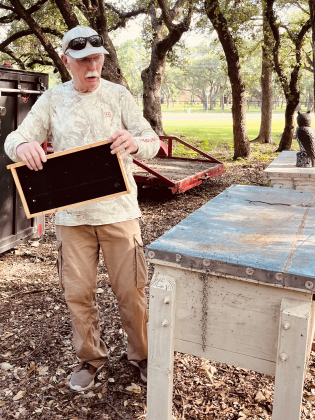 Poppers Shoppe owner Jim Ray holds a bee tray in his back yard.