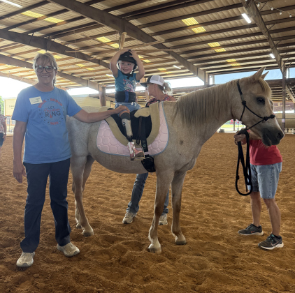 Charlee Penrod rides Sunny Girl during her lesson on July 22 with the help of ROCK volunteer Chris Miller.  Photo by Abbey Archer