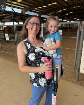 Chelsee Penrod holds her daughter Charlee, who was born without portions of her lower limbs, after her equine assisted physical therapy session.  Photo by Abbey Archer
