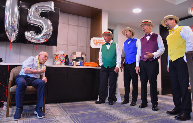 Grover Trytten, left, listens to a barbershop quartet as they sing “Happy Birthday” in four-part harmony.