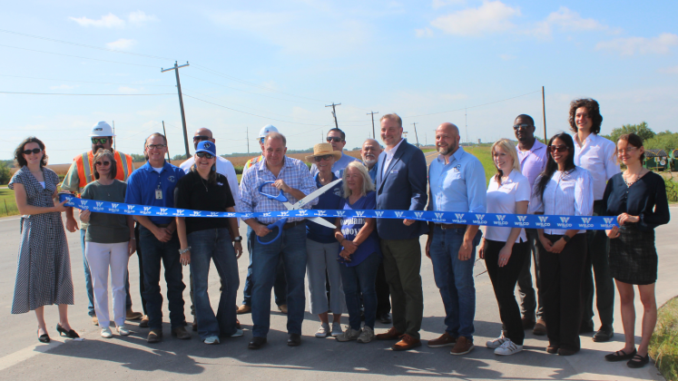  Commissioner Russ Boles, center, holds ceremonial scissors during the County Road 460 ribbon cutting on Thursday, July 30. The project helps with access to the new Coupland ISD junior high and high school.   Photo courtesy of Williamson County