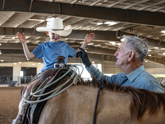 Ed Denison of Hockley, Texas, who will be 80 in October, introduces his horse named Hombre to his 8-year-old grandson Levi Bentley (wearing grandpa’s hat)   during the Texas Senior Pro Rodeo Association’s Rodeo held Sunday, August 16, 2026  at the Williamson County Expo Center.  Denison has been involved in rodeo competitions for decades.