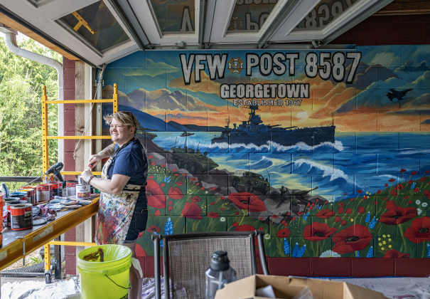 Shelby Gage stands with her 7’x25’ mural she created for the Msg. Ben D. Snowden Post 8587 on Friday, August 14, 2026.