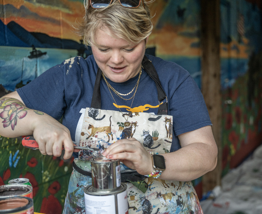 Artist Shelby Gage puts finishing touches on a 7’x25’ mural she created for the Msg. Ben D. Snowden Post 8587 on Friday, August 14, 2026. Gage, a Navy veteran, spent over 100 hours painting the mural.  On Friday she was adding to clear coat to protect her work.  A dedication is planned for August 24th, the 59th birthday of this post.  Photo by Andy Sharp