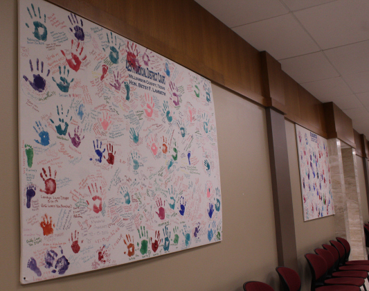 Two of three canvases are filled with the handprints of children and their families that Judge Lambeth has legalized adoption for. Prior to her time on the bench, Ms. Lambeth was a family lawyer. Photo by Nalani Nuylan.