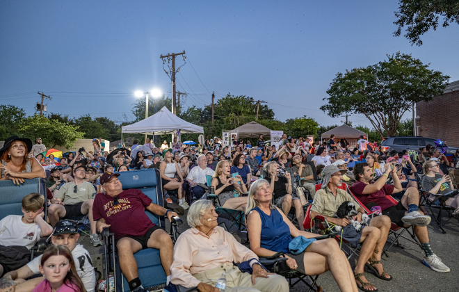 A crowd watches as  Purple Martins gather in the sky over Greenlawn Crossing Shopping Complex on Friday, July 31, 2026.
