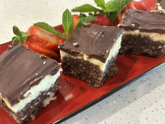 essamy’s Nanaimo Bars are plated with mint and strawberries on the side. 