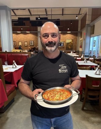 Owner of Tony &amp; Luigi’s Jamie Cohen holding an order of lasagne in the dining room. Photo by Abbey Archer