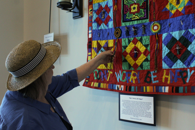 Sun City artist Susan Hoppenworth explains the significance of the Guatemalan belts and bookmarks in her quilt “Don’t Worry, Be Happy.” The quilt is one of nine on display in a 9/11 memorial gallery in Sun City. Photo by Nalani Nuylan.