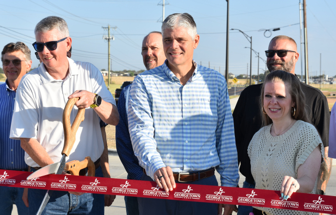 From left, Georgetown Council Member Ben Butler, City Manager David Morgan and Mitchell Elementary School Principal Melanie Moore cut the ribbon for Rockride Lane. (Photo by Kaitlyn Wilkes) 