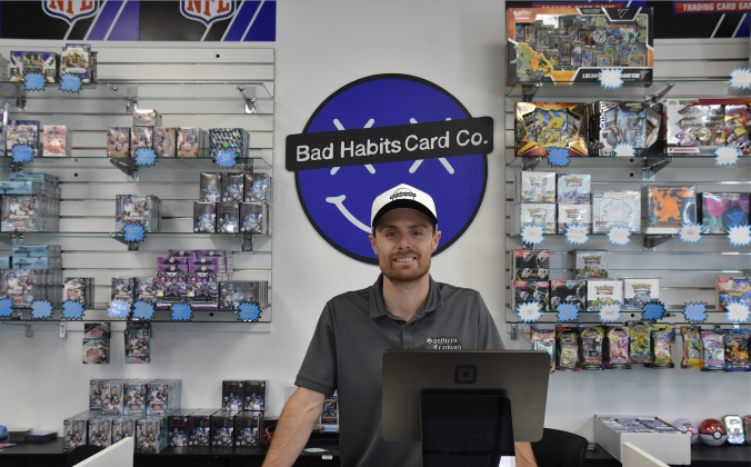 Brodie Sachs, owner of Bad Habits Card Co., stands in front of a portion of the trading cards available for purchase. (Photo by Kaitlyn Wilkes)