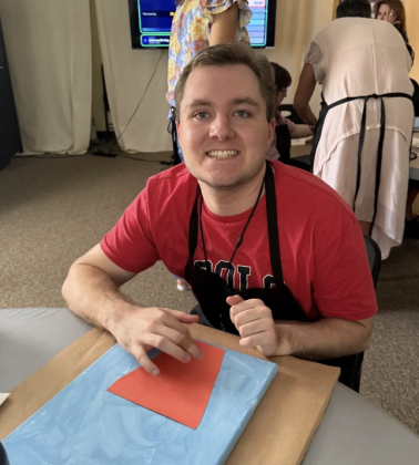 Dylan Shellberg gluing his construction-paper vase onto the canvas.