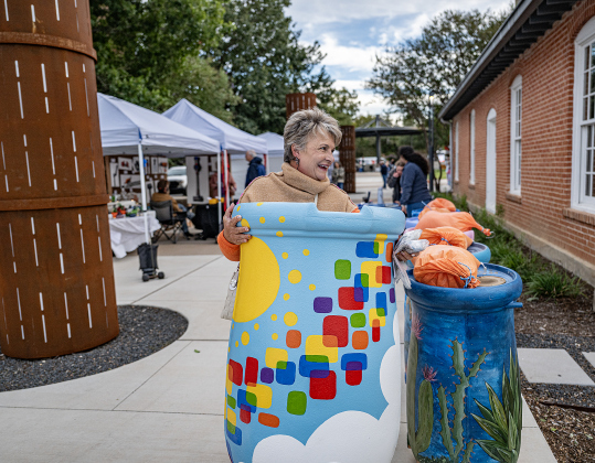 Renee Hewett is pictured at the Light & Waterworks District area as she totes a colorful rain barrel that she won after a winning auction bid during Georgetown’s Art Stroll on Friday, October 16, 2026. Photo by Andy Sharp