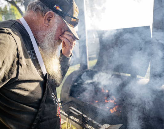 Dave Reed wipes the smoke from his eyes while keeping a close eye on hamburgers being grilled during the Third Annual St. Peter Lutheran Church Hamburger Fundraiser on Saturday, October 17, 2026. A Country Store and Quilt Raffle were also held. The church is at 2929 FM 972 in Walburg. Photo by Andy Sharp