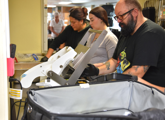 Volunteers at the Madella Hilliard Senior Center, 803 West Eighth Street, pack meals and vacuum seal them for lunchtime delivery for Meals on Wheels. (Photo by Kaitlyn Wilkes)