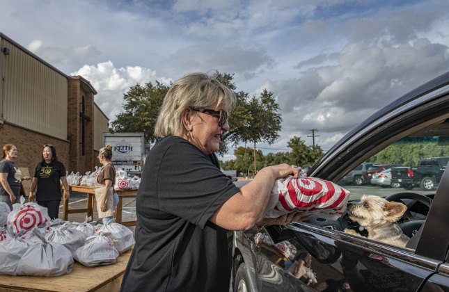 Zachary, a dog owned by Perry and Judy Hanson, takes a sniff of to-go dinners being delivered by Susan Holmstrom Monday, November 7.