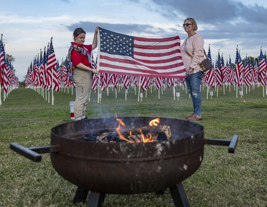 Left, American Heritage Girls troop member Maria Combs, 15, left, and Army veteran Wanda Clark, right, prepare a flag for retirement the evening of Wednesday, November 9.