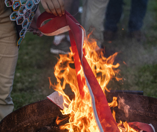 Pieces of an American flag are placed into a fire pit for proper retirement.