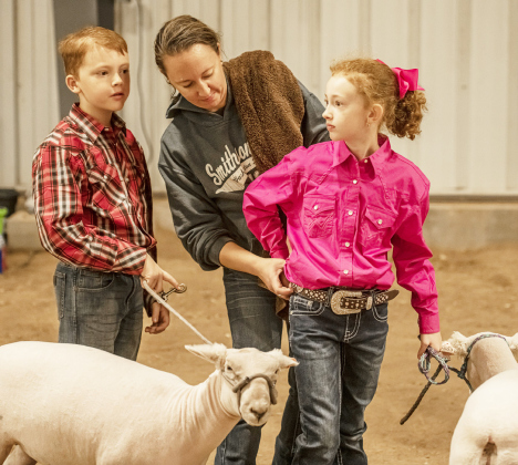 Timothy Blume, 10, left, with his sheep, Cotton, waits to enter the arena while mom Amy Blume, makes a clothing adjustment for Timothy’s sister Abby, 8, who was showing her sheep, Pixie.