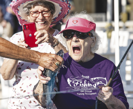 Bertha Pistone, 98, reacts to a fish she just caught while her daughter Mary Ann Eskew takes a photo Friday during “Gone Fishing,” the 19th Annual Fishing Tournament held at SPJST Senior Living in Taylor. The two-day event began Thursday with a large pool loaded with 500 pounds of catfish set up on the grounds. The tournament culminated Friday afternoon and evening with awards and a fish fry. — Photo by Andy Sharp