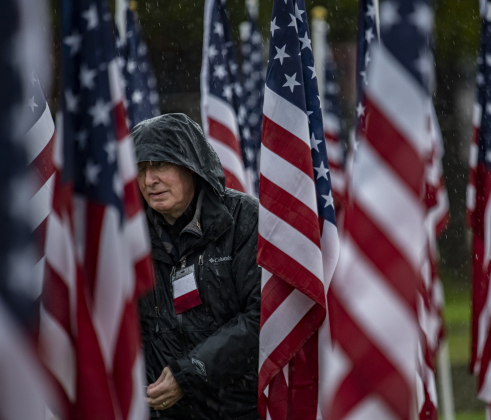 Georgetown Field of Honor volunteer Larry Deal braves the elements to secure tags on American flags during a blustery and rainy Veterans Day, Friday, November 11.