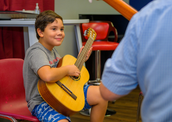 Liam Brown, 7, learns to play on a donated guitar.