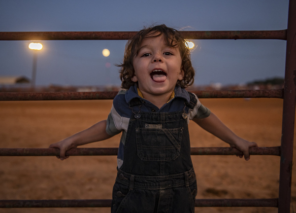 Josiah Bellow, 3, enjoys a cool evening after the sun has set. In the distance behind him, an almost full-moon glows.