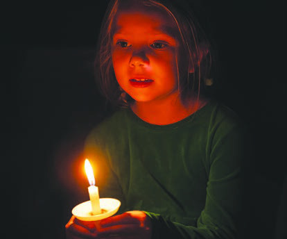 Zinnia Crenshaw, 6, holds her candle while singing carols.