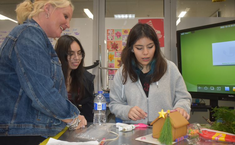 Floral Design instructor Amy Beran works with Georgetown High School senior floral students Jasmin Garcia Camargo and Lydia Rojas on creating gingerbread houses incorporating floral elements. (Katherine Anthony)