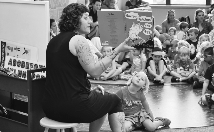 Kalena Powell, library assistant, reads to children, including Allie Williams, during storytime in 2015. (Sun Archive)