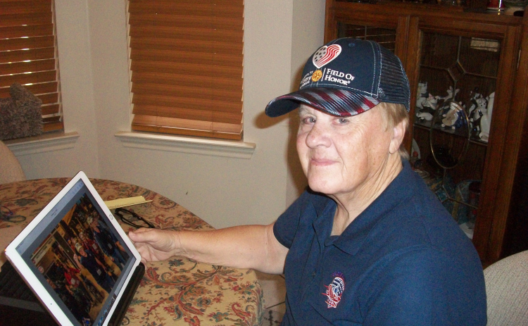 Frances “Fay” Pool, a 21-year Army veteran, enjoys reminiscing over photographs from her recent Honor Flight Austin trip to Washington, D.C., where Ms. Pool and other veterans visited many of the city’s monuments and memorials. The cap she’s wearing is from the Georgetown Rotary Foundation’s 2022 Field of Honor. (Photo by Brad Stutzman)