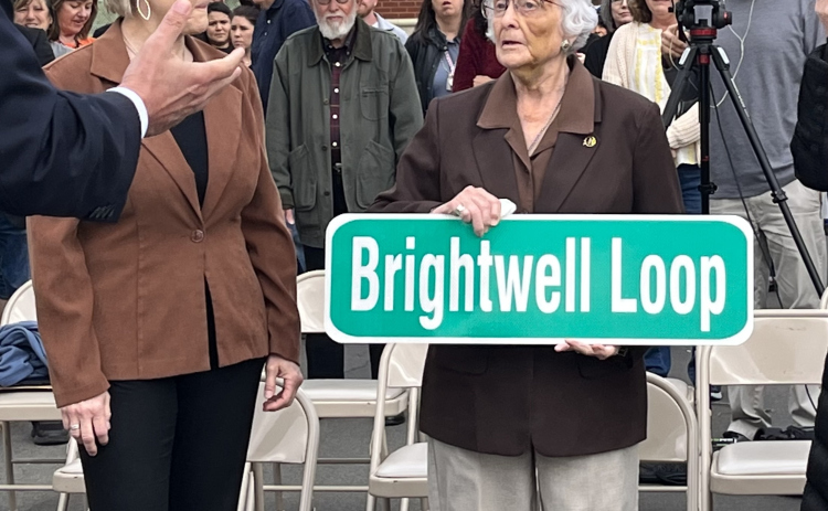 Barbara Brightwell holds a commemorative sign for the road named after her and her husband, George.